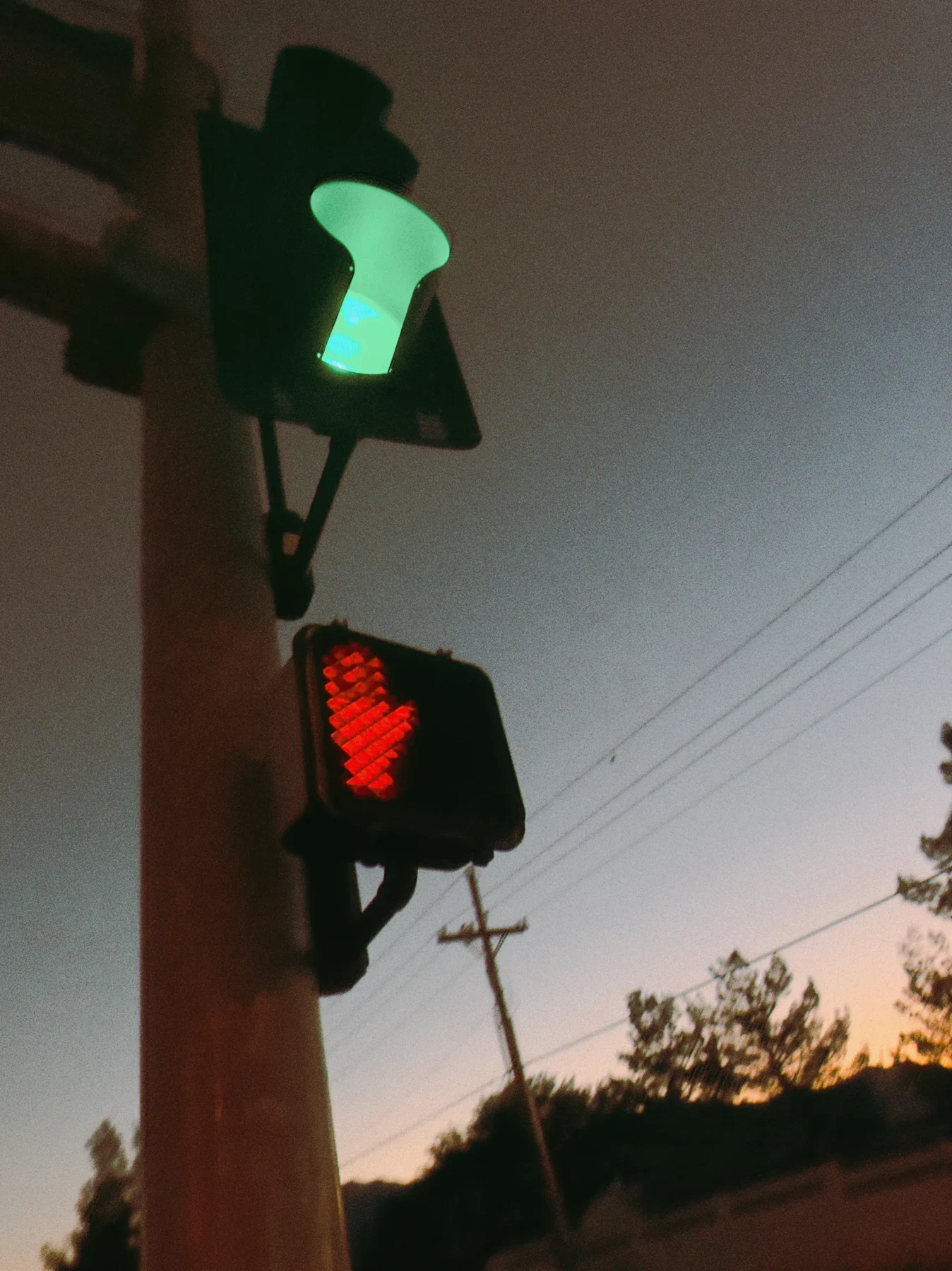 Green and red pedestrian signals against the evening sky