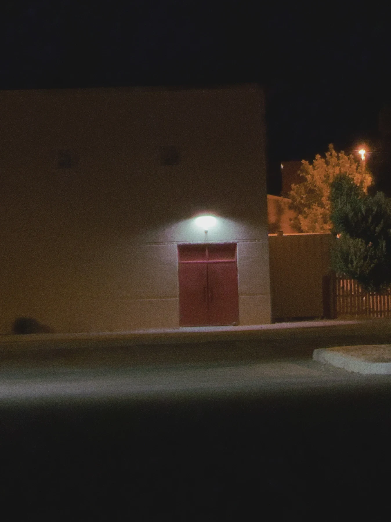 A red door beneath a light on an empty street